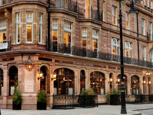 Historic brick building with ornate balconies and The Adam and Eve Public House ground floor