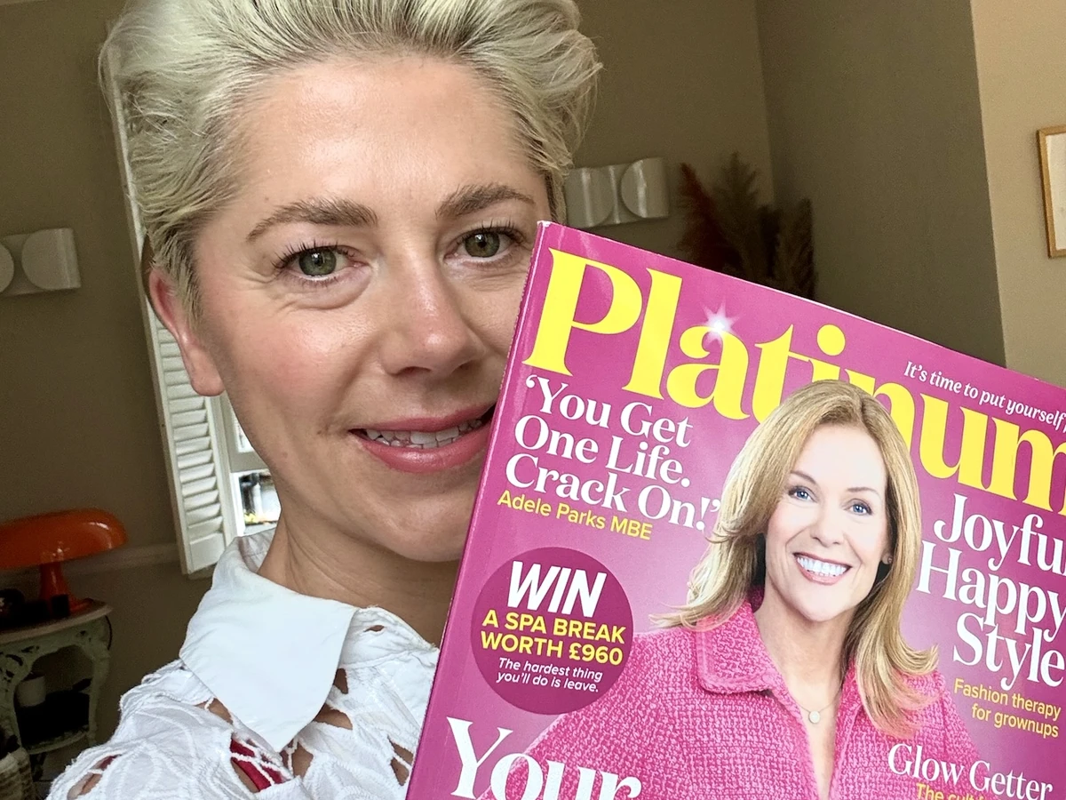 Woman holding a pink Platinum magazine featuring Adele Parks and a smiling woman