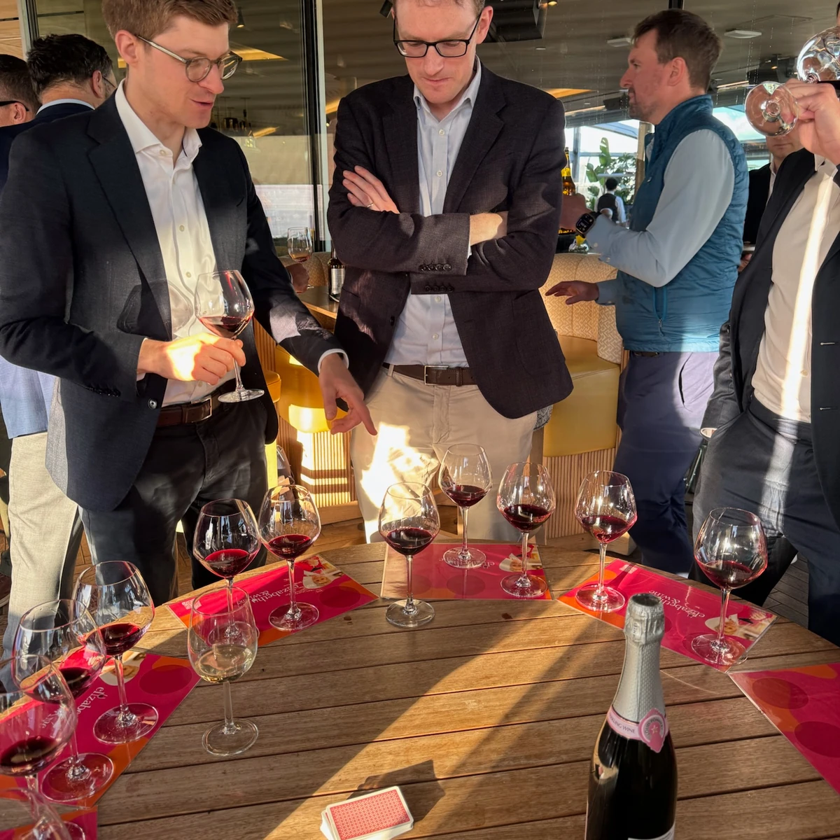 People gathered around a table of red wine glasses and a champagne bottle