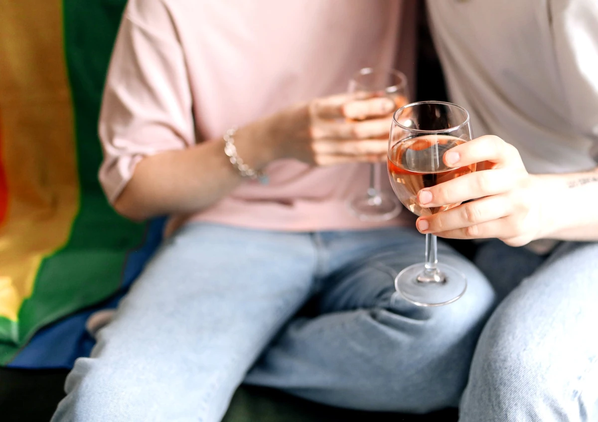 Two people holding glasses of rosé wine while seated beside each other