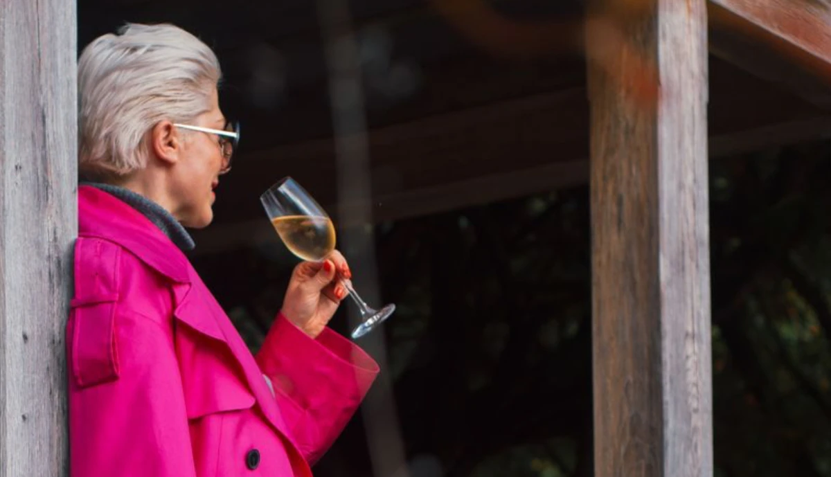 Woman in pink coat holding a glass of white wine