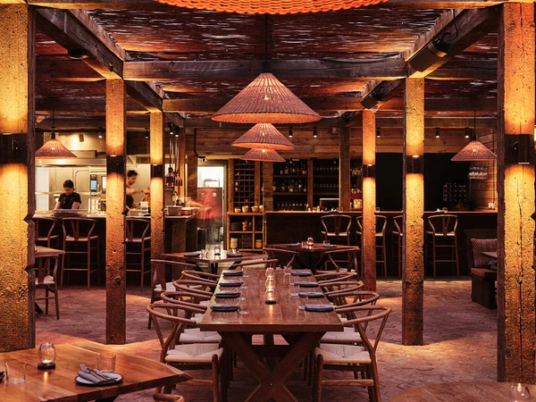 Rustic restaurant interior with wooden tables, chairs, pendant lights and bar shelves