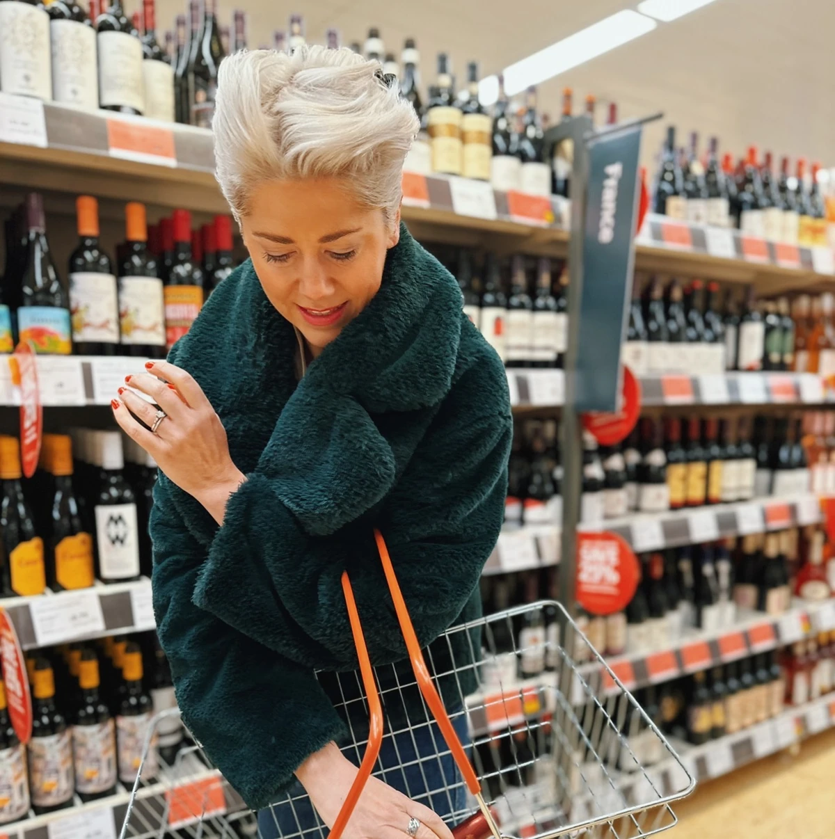 Woman in dark coat standing beside a shopping trolley in a wine shop