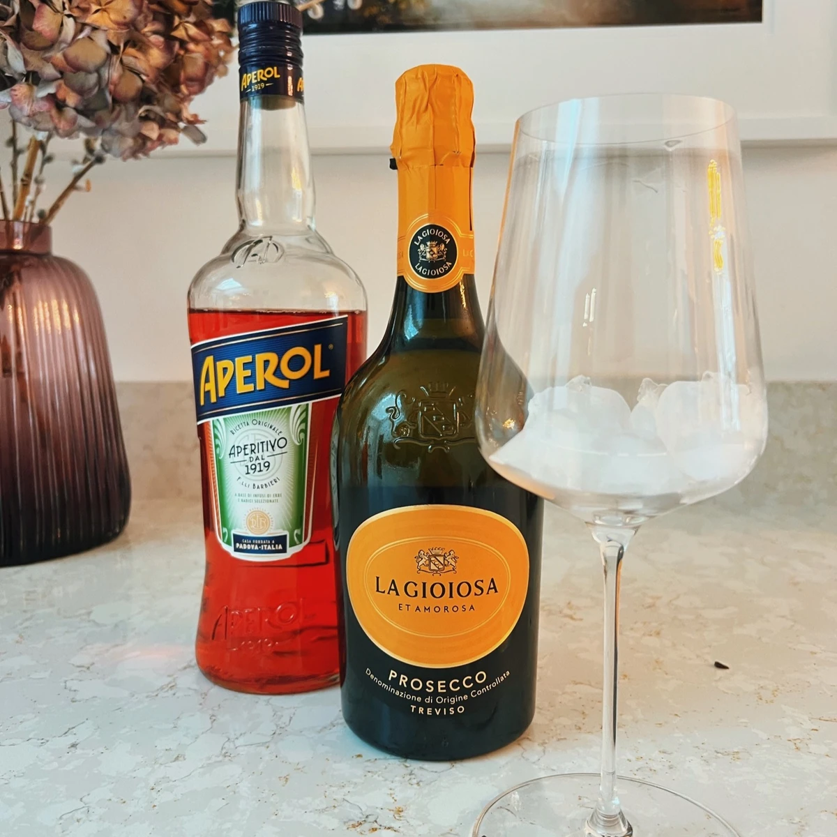 Aperol and La Gioiosa Prosecco bottles beside a glass filled with ice