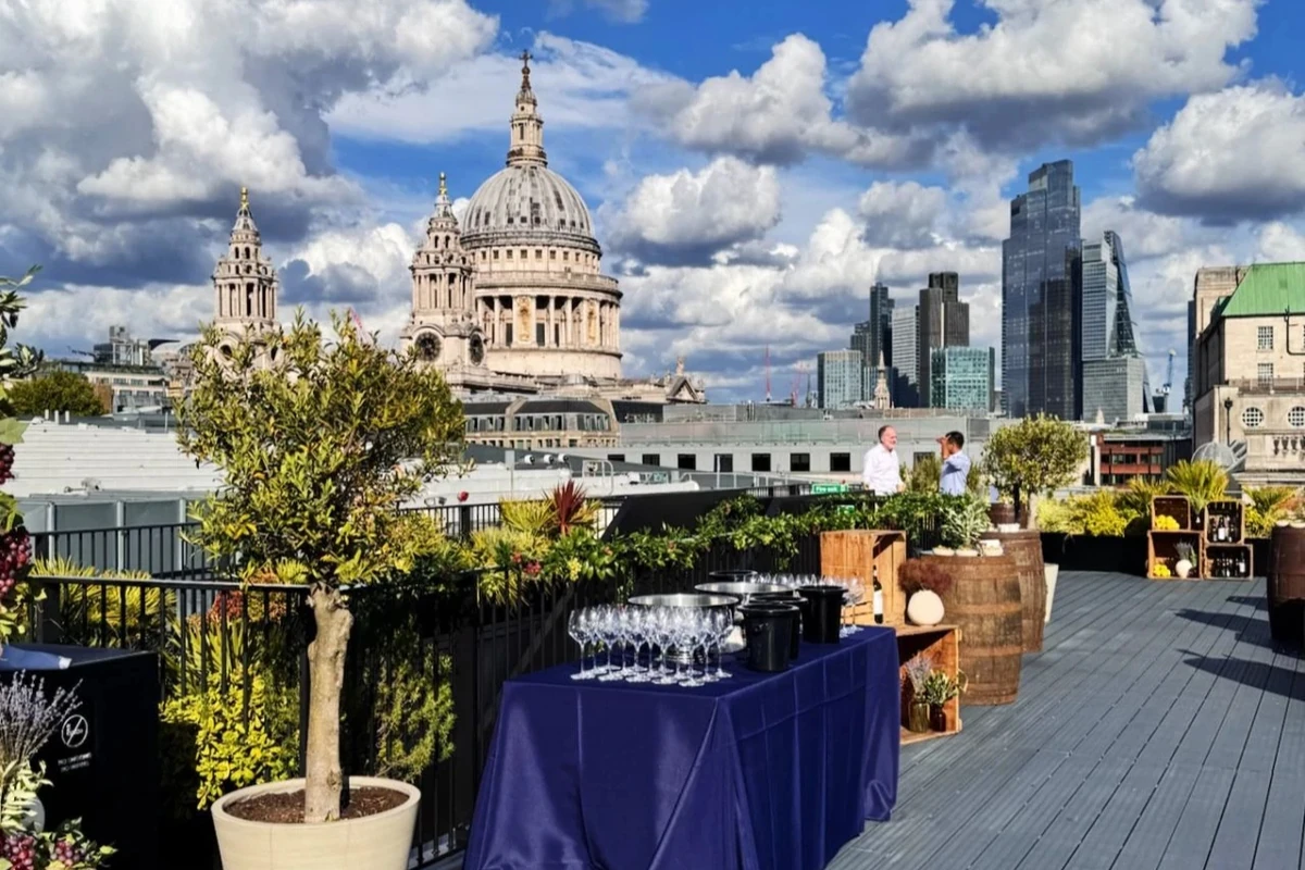 Rooftop terrace with wine glasses, plants and views of St Paul’s Cathedral and London skyline