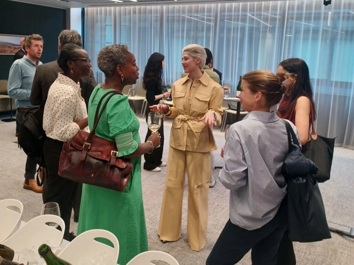 People mingling at a wine event, holding wine glasses in a modern room