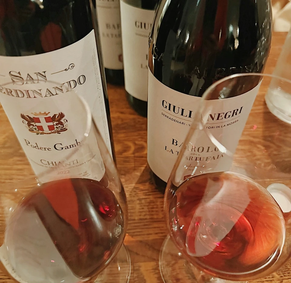 Barolo wine bottles and glasses of red wine on a wooden table