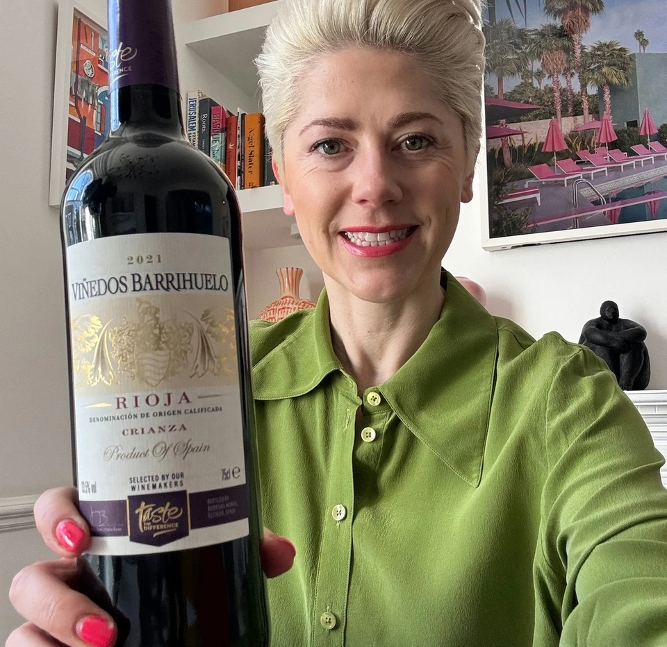 Smiling woman holding a bottle of 2021 Viñedos Barrihuelo Rioja Crianza