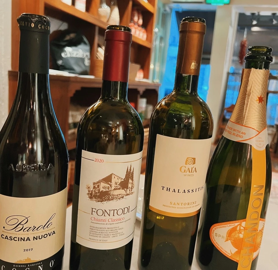 Four wine bottles, including a Barolo Cascina Nuova, displayed on a restaurant table