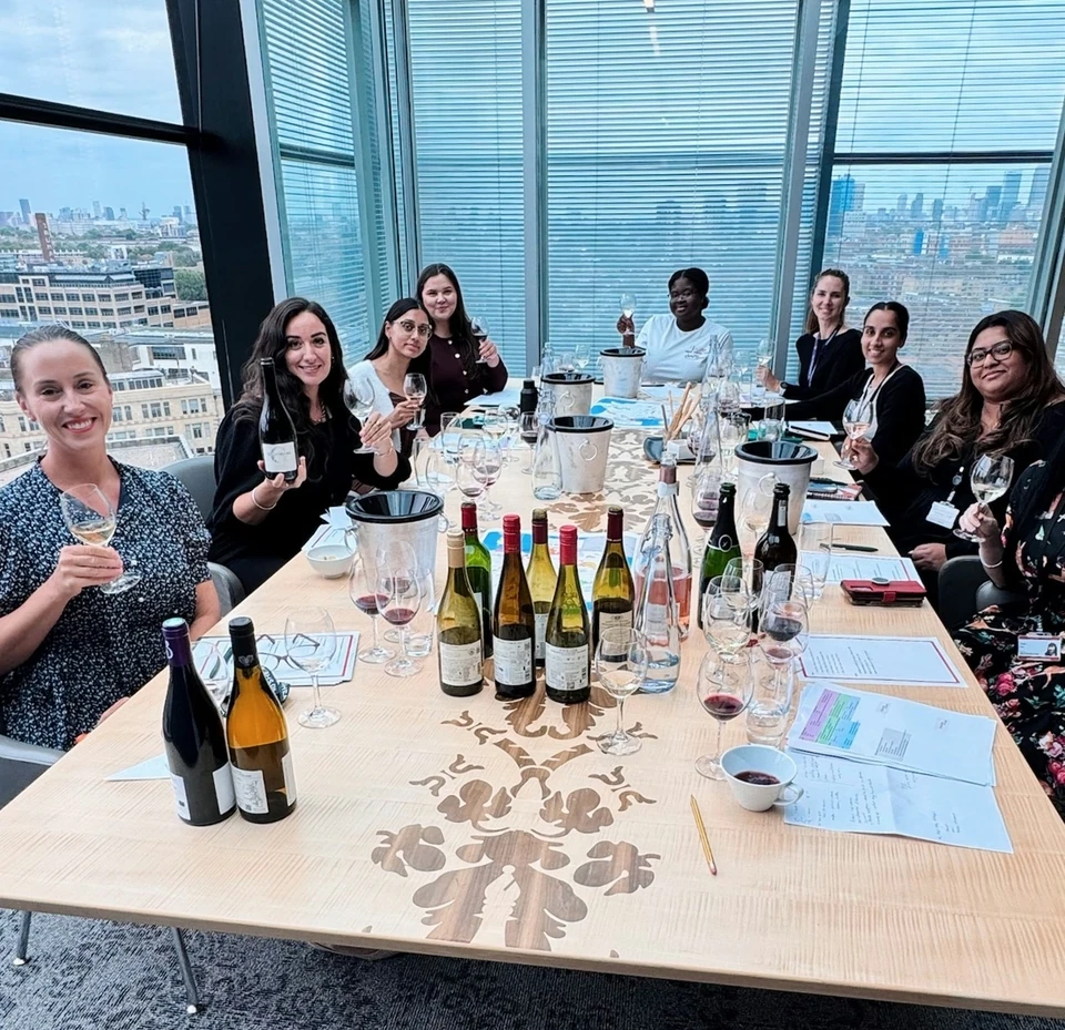 Group wine tasting around a conference table with London visible through the windows