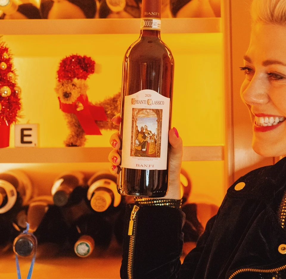 Woman holding a bottle of Banfi Chianti Classico in front of a wine display