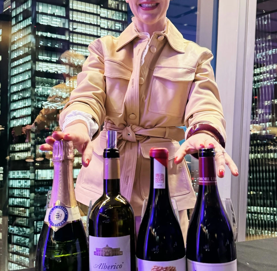 Wine presenter standing behind four wine bottles, including one labelled Syrah