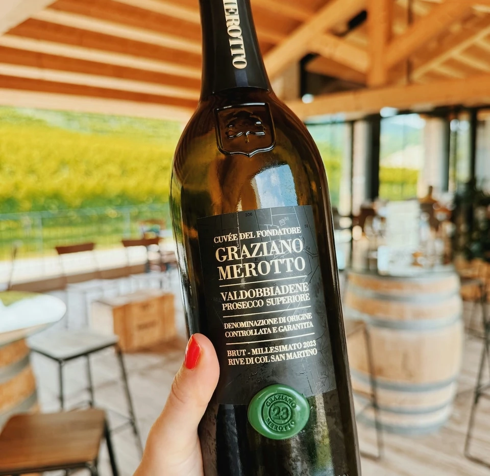 Bottle of Graziano Merotto Valdobbiadene Prosecco Superiore in a bright winery tasting room