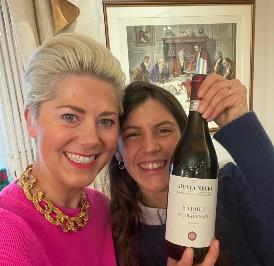 Two women hold a bottle of Giulia Negri Barolo Serradenari