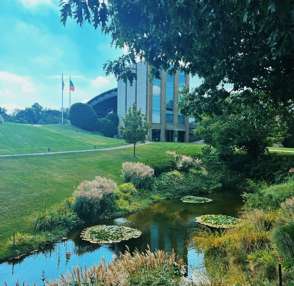Ca' del Bosco winery building beside a landscaped pond, lawns and flags