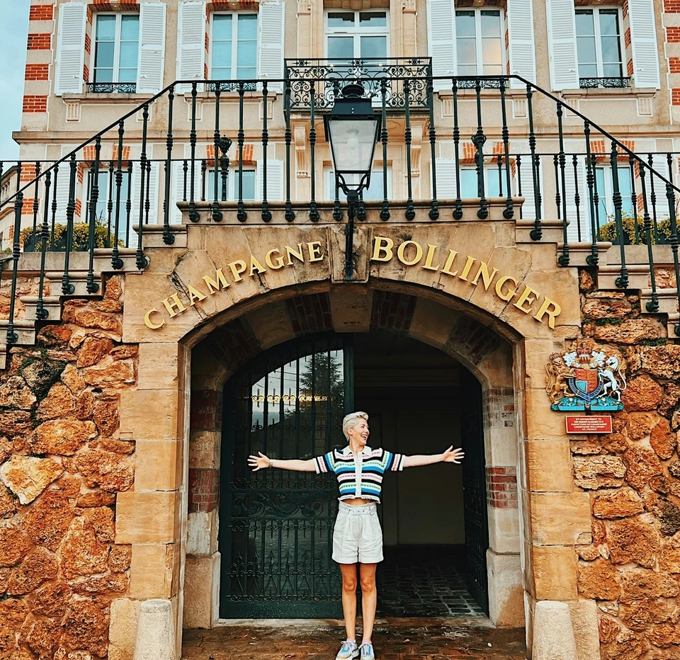 Person with arms outstretched beneath the Champagne Bollinger entrance