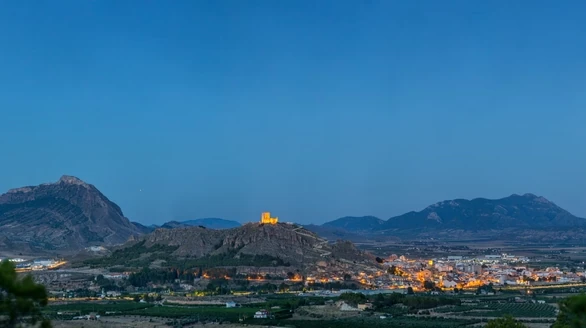 Twilight view of a Spanish wine-growing landscape with vineyards, mountains, a town and the rising moon