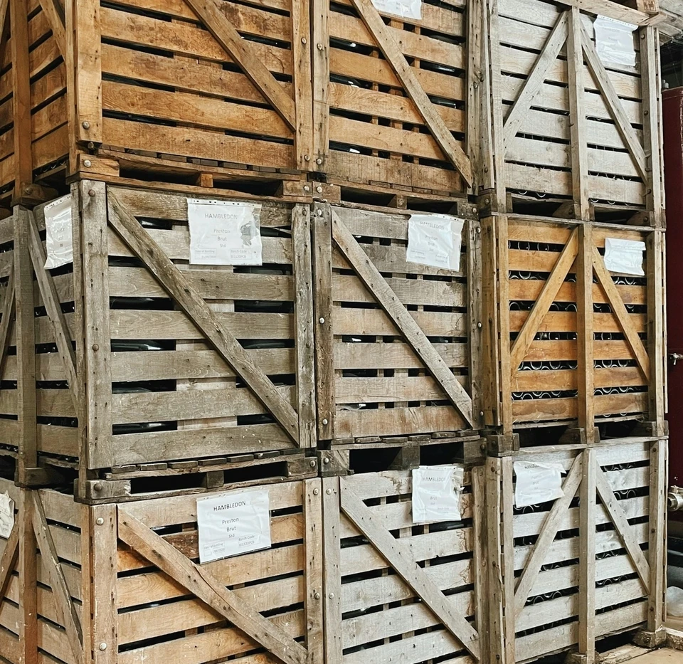 Wooden wine crates stacked in a cellar, labelled Hambledon Preston Brut