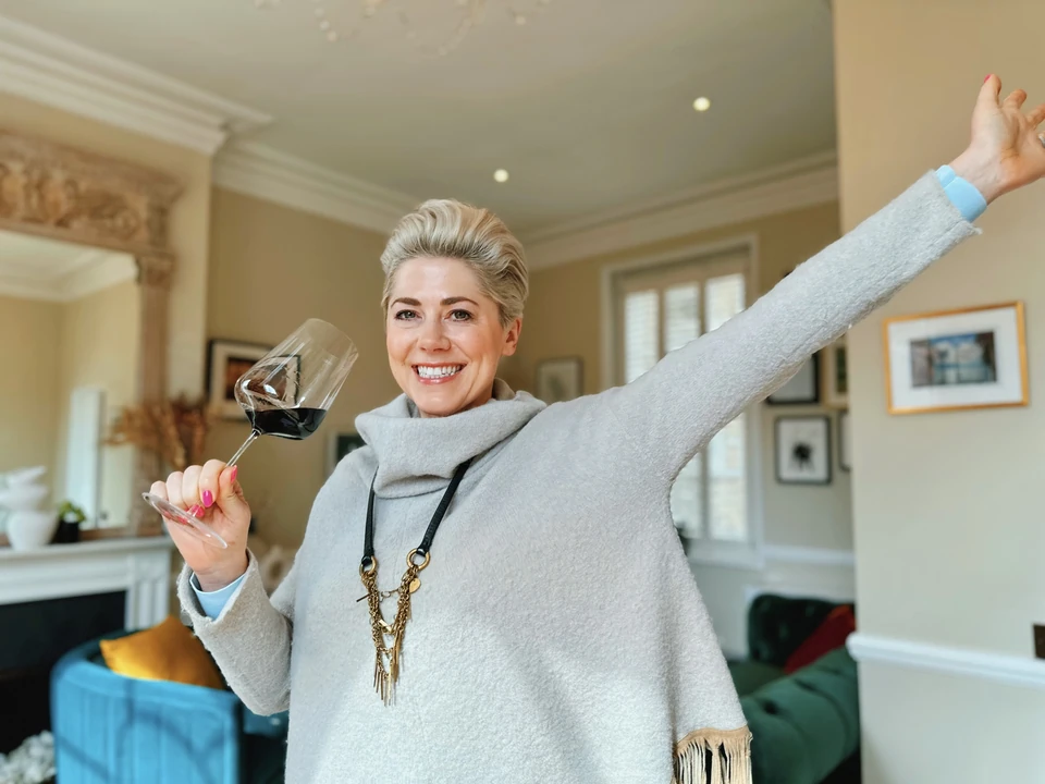 Woman raising a glass of red wine in a sitting room