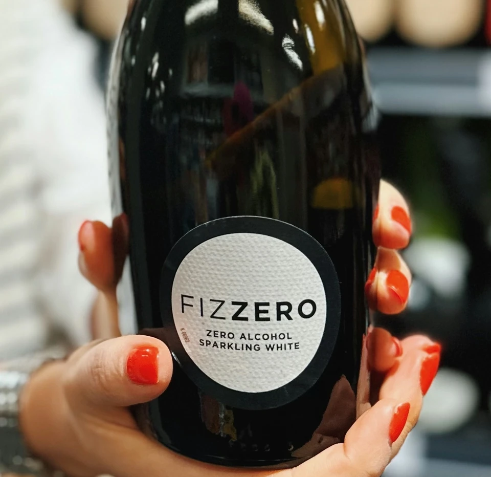 Hands holding a bottle of Fizzero zero alcohol sparkling white