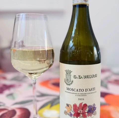 Bottle of Moscato d’Asti beside a glass of pale sparkling wine