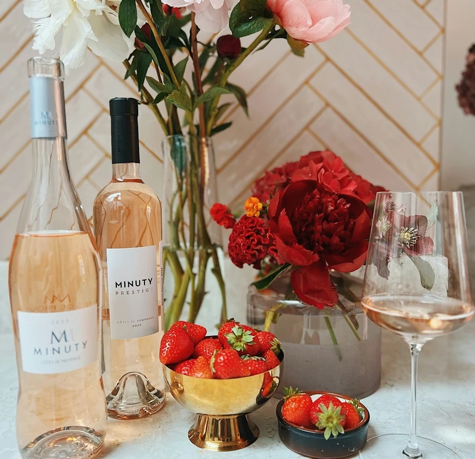 Minuty rosé bottles with strawberries, flowers and a filled wine glass