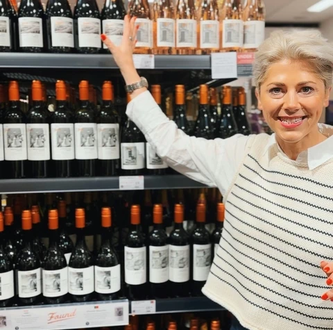 Woman pointing to Found wine bottles on a supermarket shelf