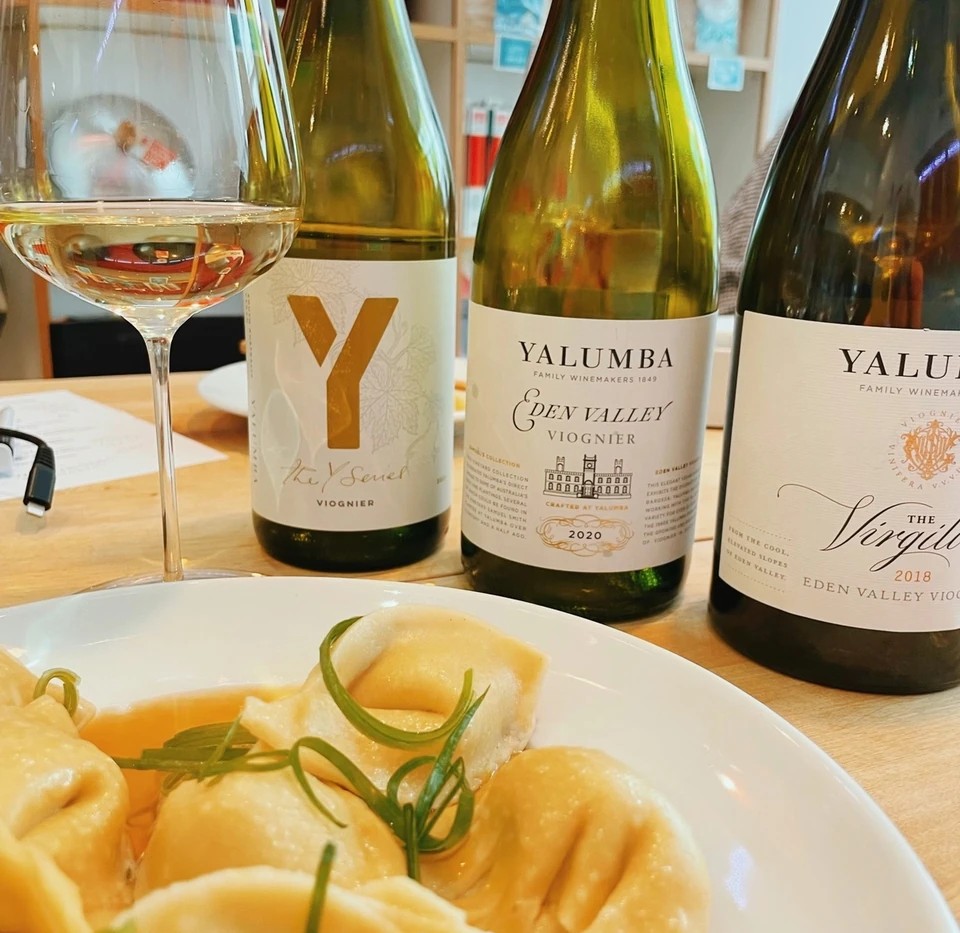 Glass of Viognier with three Viognier bottles and filled pasta on a plate