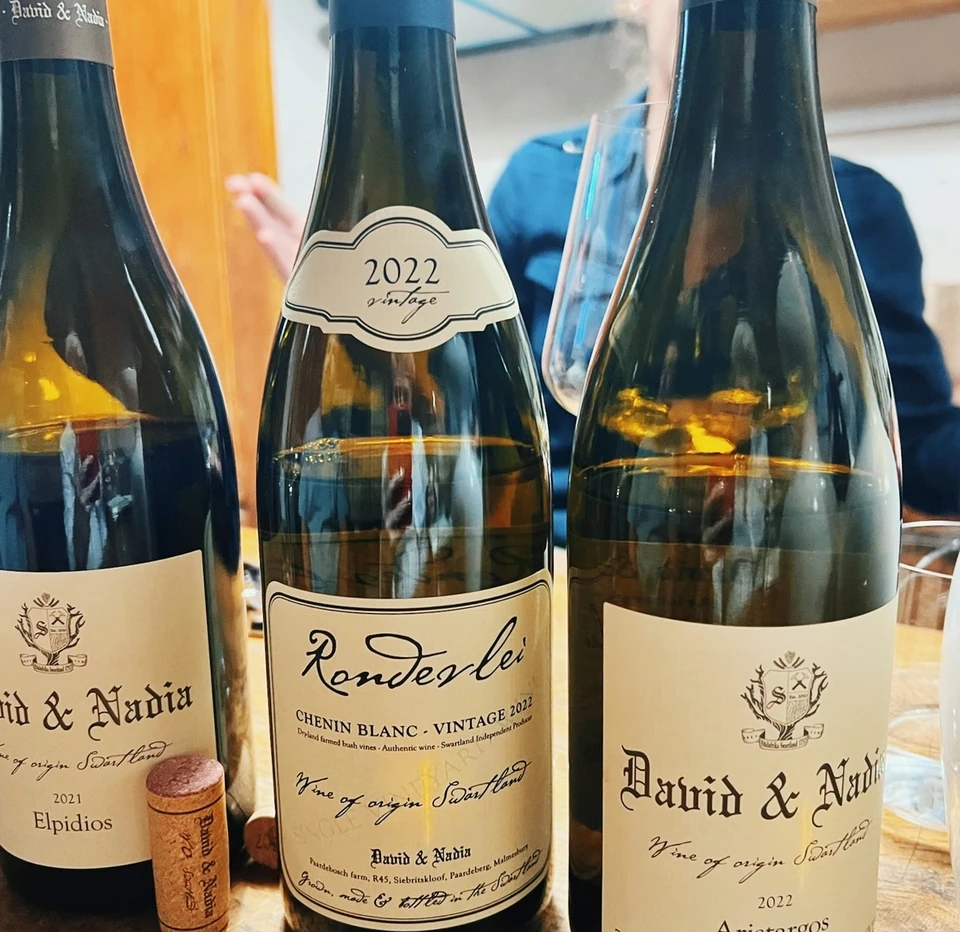 Three David & Nadia wine bottles, including 2022 Rondeerlei Chenin Blanc, on a wooden table