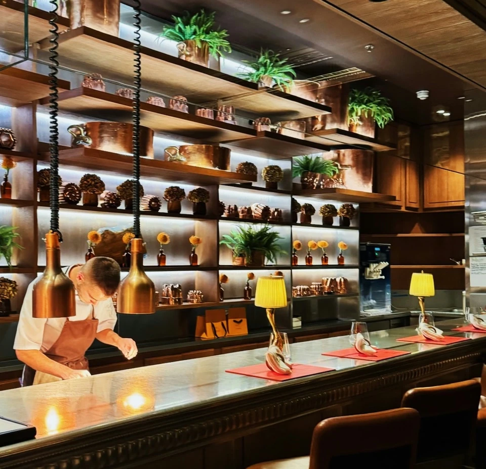 Restaurant bar with a chef, pendant lights, plants and laid tables