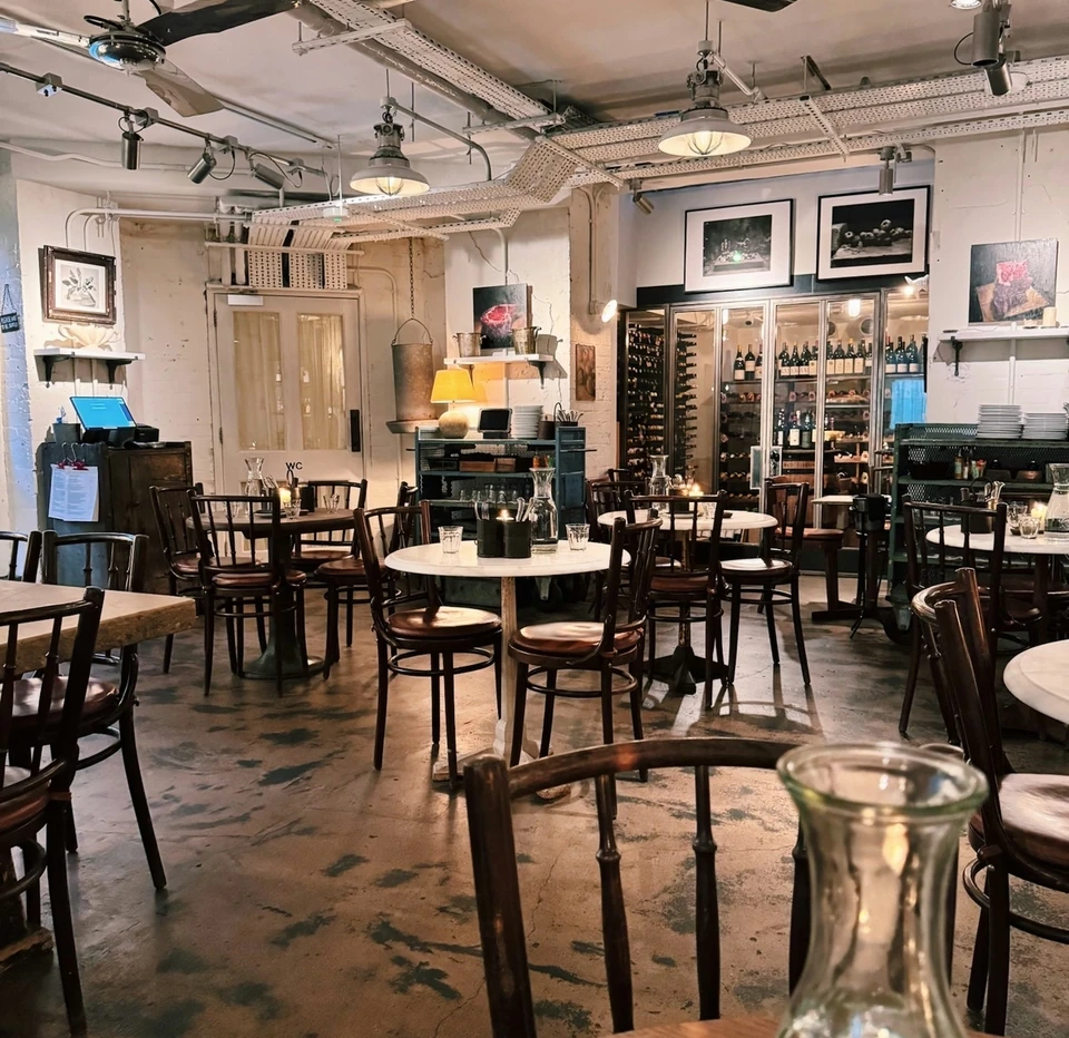 Rustic farm shop restaurant with wooden tables, wine shelves, pendant lights and ceiling fans