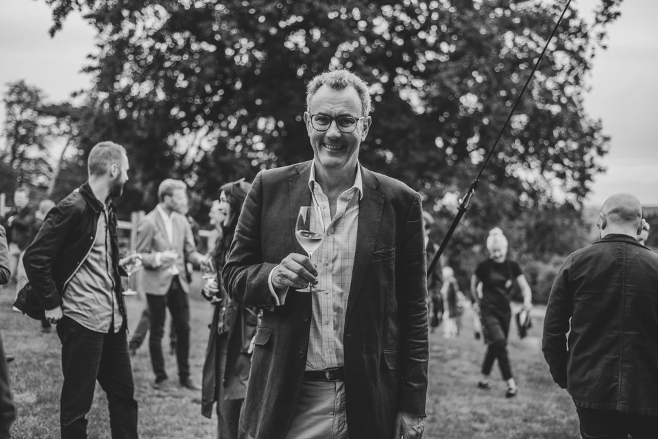 Guests mingle outdoors at a networking event, with a man holding a glass of wine