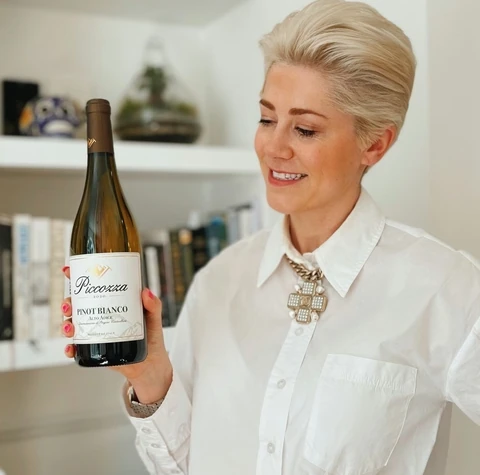 Woman in a white shirt holding a bottle of Piccorsa Pinot Bianco