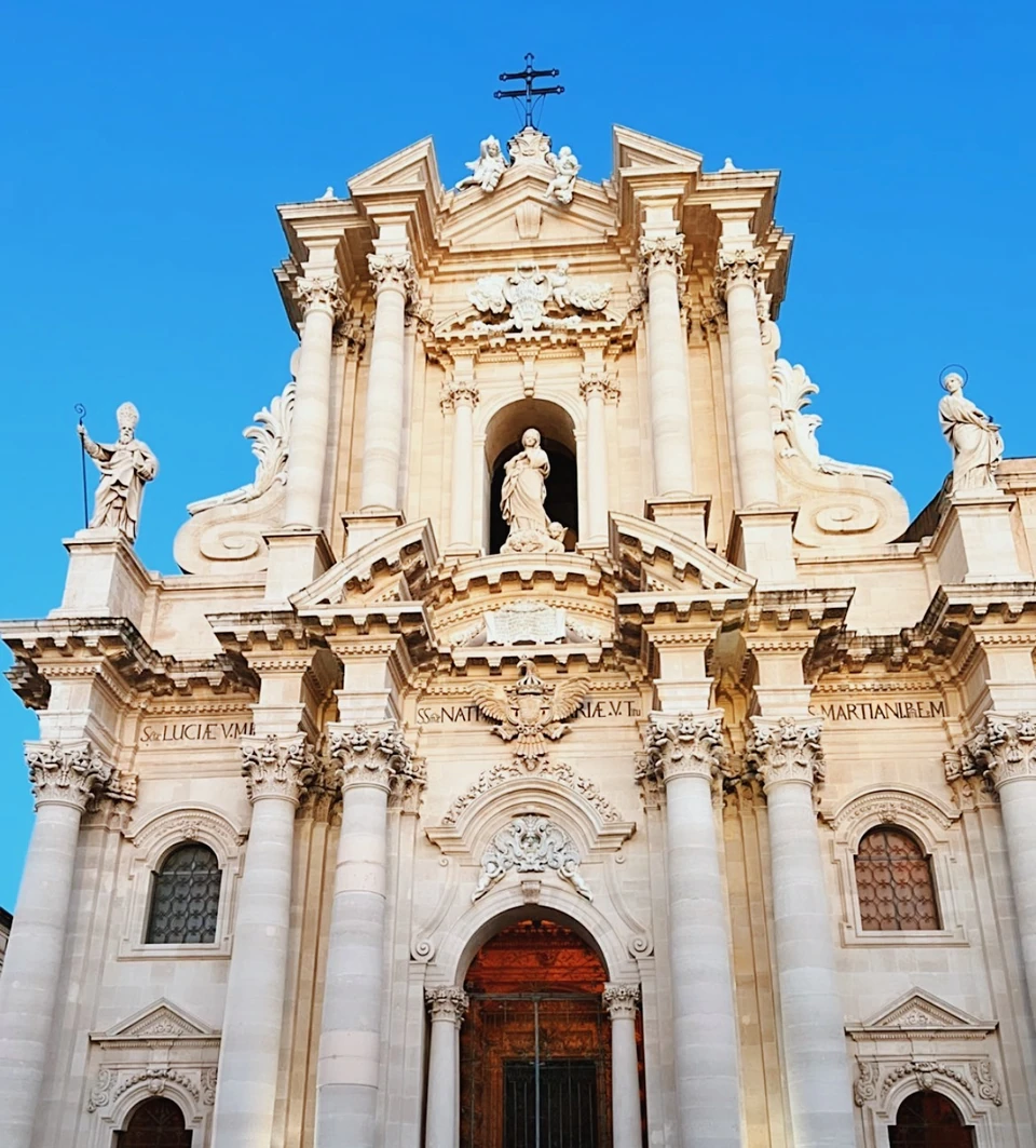 Ornate Baroque church façade beneath a vivid blue sky in Sicily
