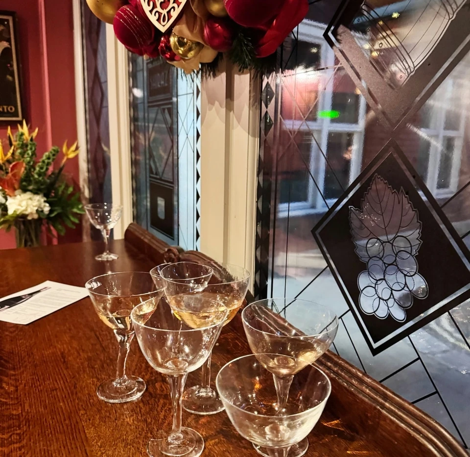 Christmas decorations and glasses of pale wine on a wooden table beside a stained glass window