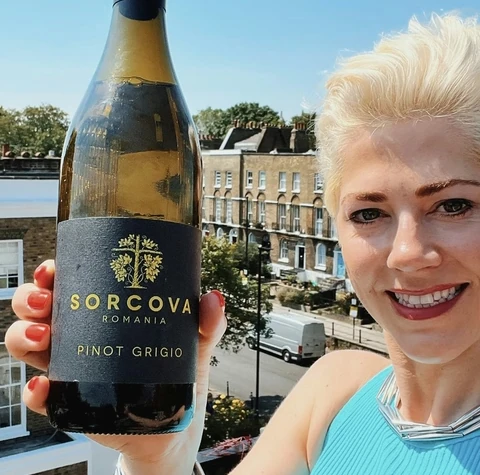 Woman holding a bottle of Sorcova Romania Pinot Grigio on a sunny balcony