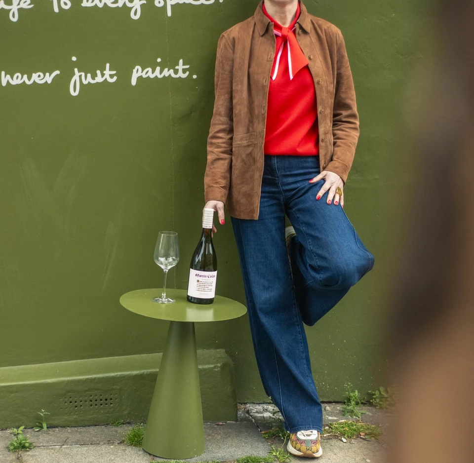 Person holding an Albariño bottle beside a wine glass