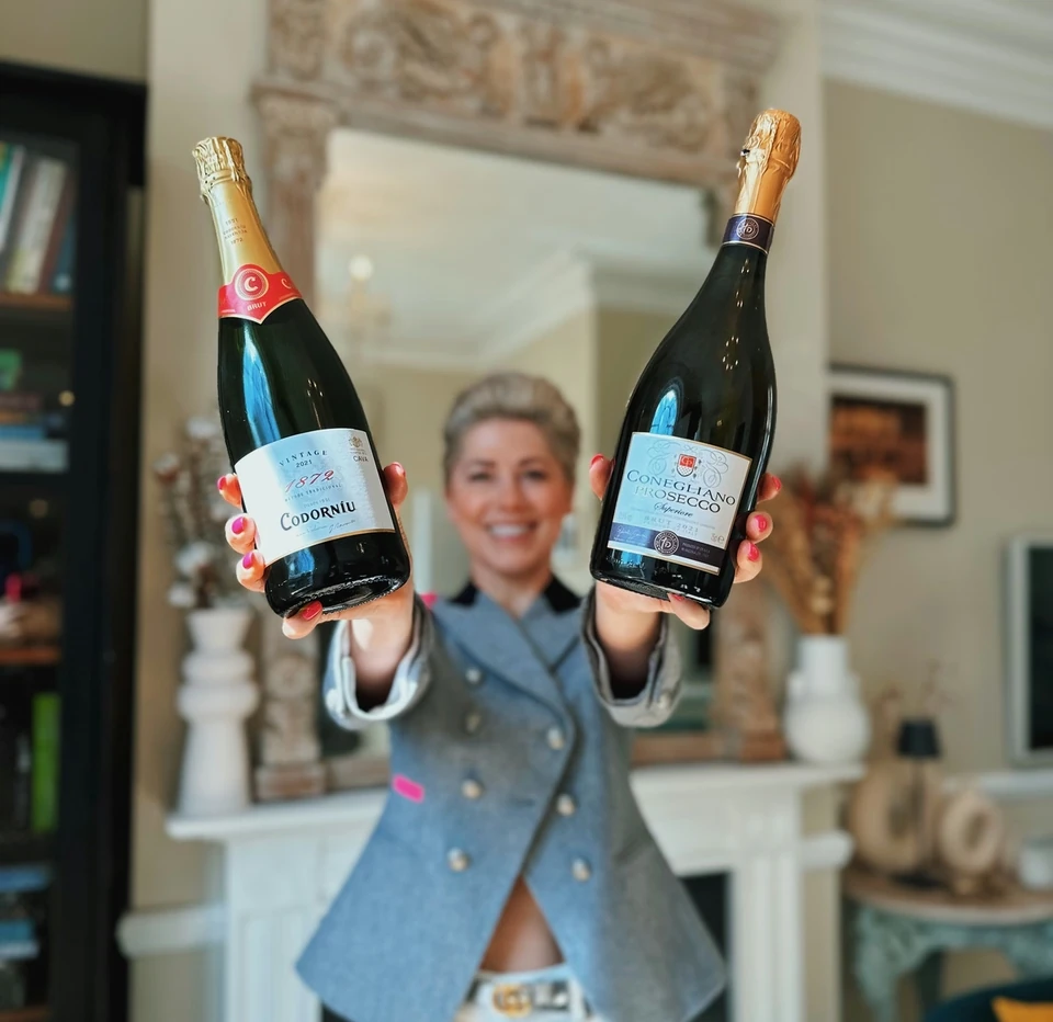 Person holding bottles of Codorníu Cava and Conegliano Prosecco