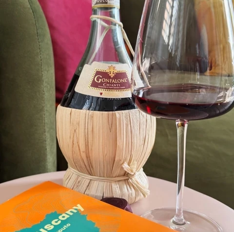 Gonfalone Chianti bottle beside a glass of red wine and a Tuscany wine guide