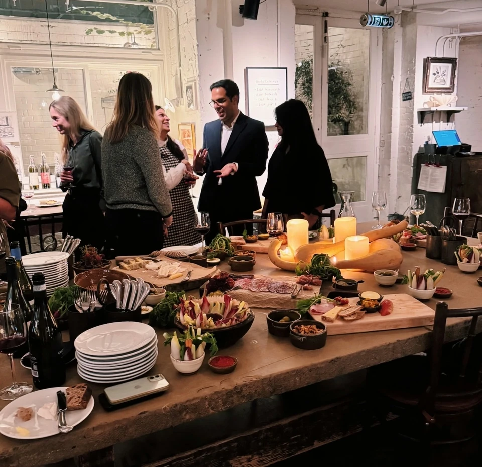 Guests gather around a wine and food table in a farm shop