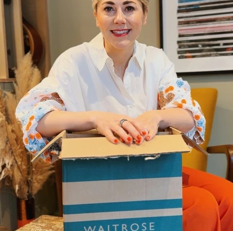 Woman opening a Waitrose & Partners box at a table
