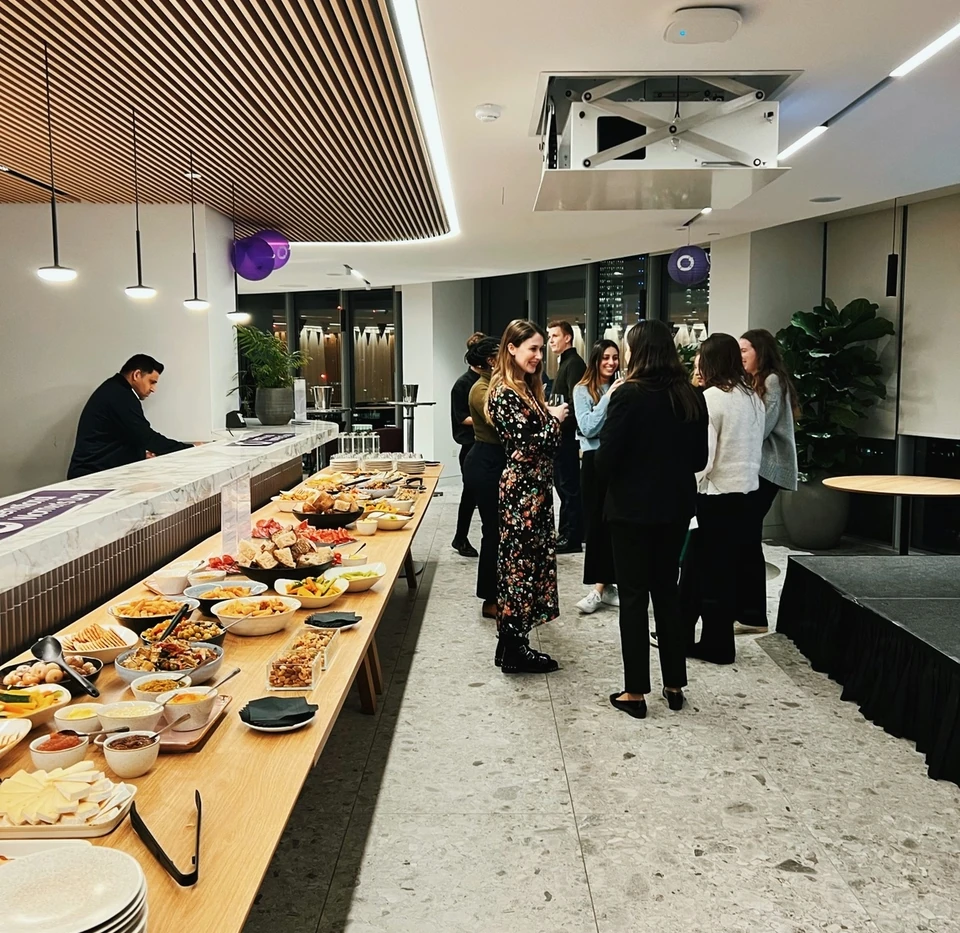 Guests mingle beside a buffet at a wine tasting for Simpson Thacher and Barrett