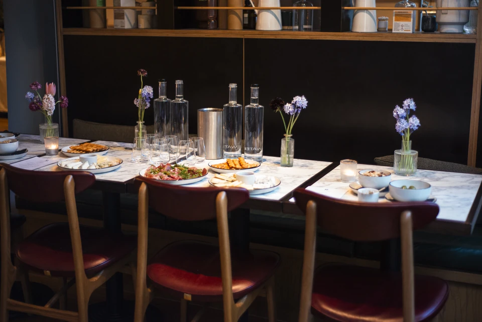 Marble dining tables set with wine glasses, water bottles, flowers and sharing plates