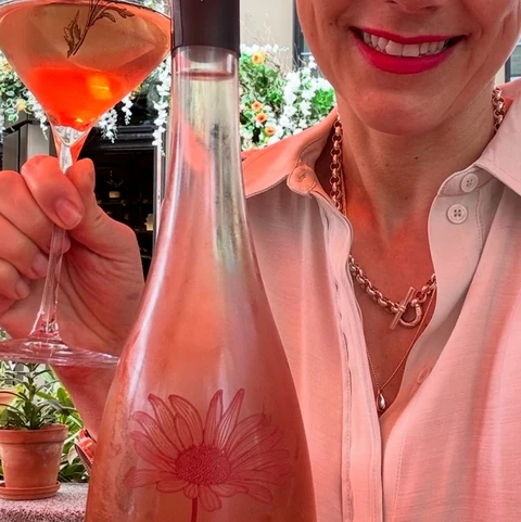 Woman holding a glass of rosé beside a Château Sainte Marguerite bottle