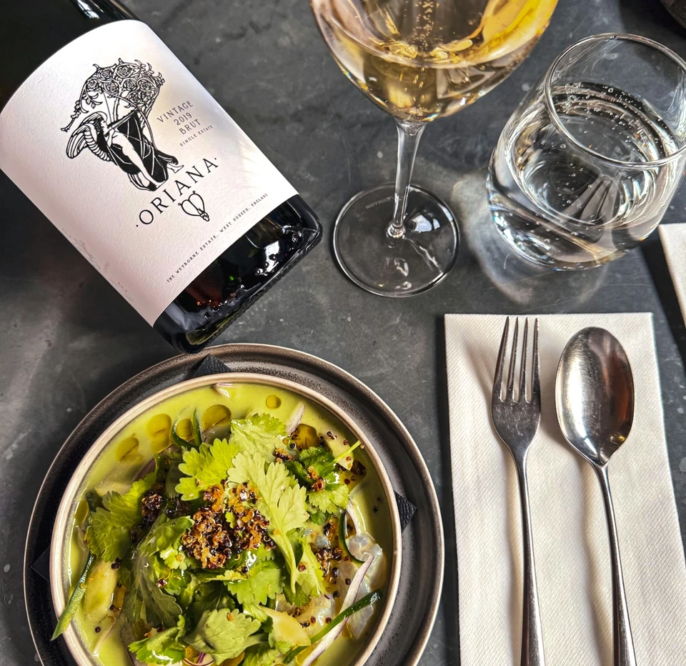 Ornella 2019 English sparkling wine with a glass, water and a herb-topped dish