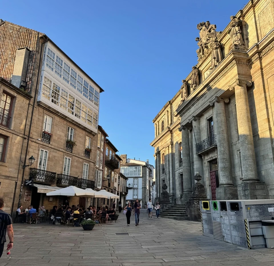 Historic city square in Rías Baixas with a grand stone building, traditional houses and a busy outdoor café