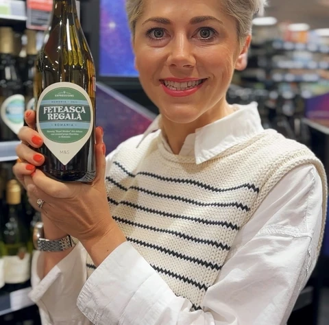 Woman holding a bottle of Fetească Regală wine in a shop