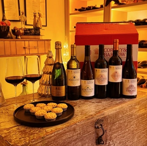 Corney & Barrow wines, glasses and mince pies arranged on a wooden table