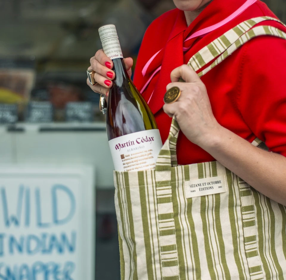 Person in a red top holding a Martín Códax Albariño bottle while wearing a striped apron