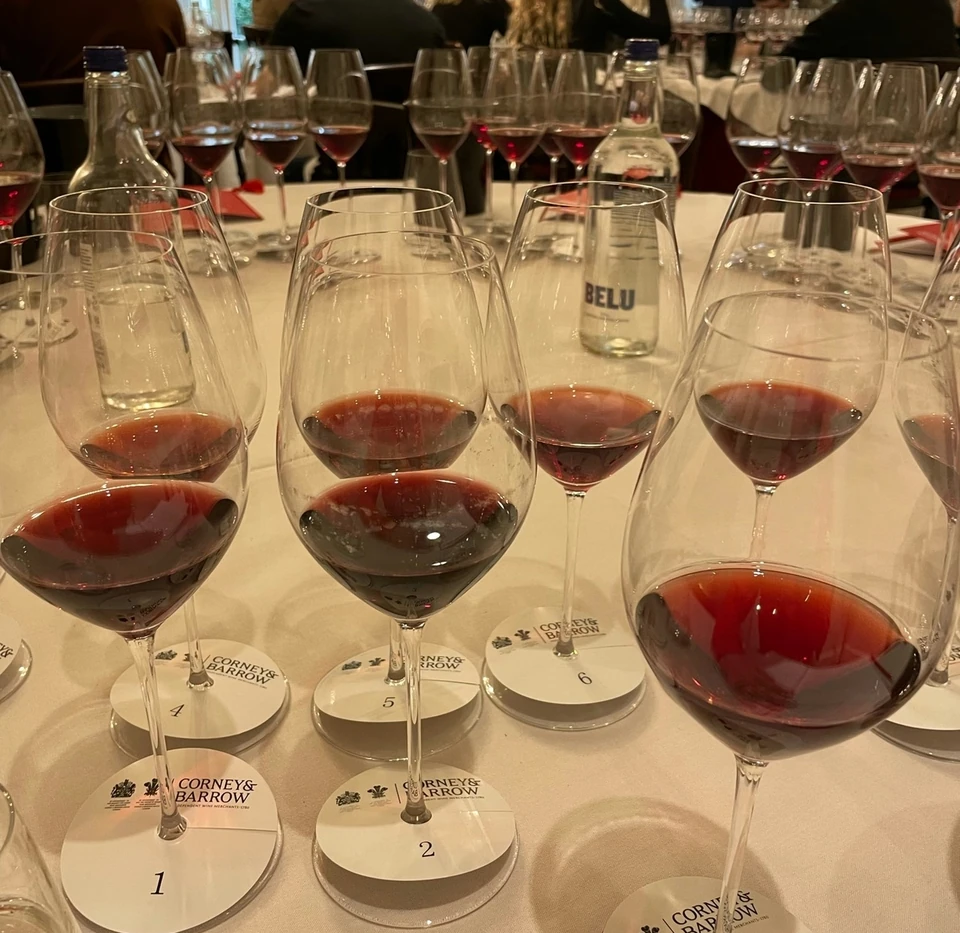 Corney & Barrow wine tasting with numbered glasses of red wine and guests seated behind